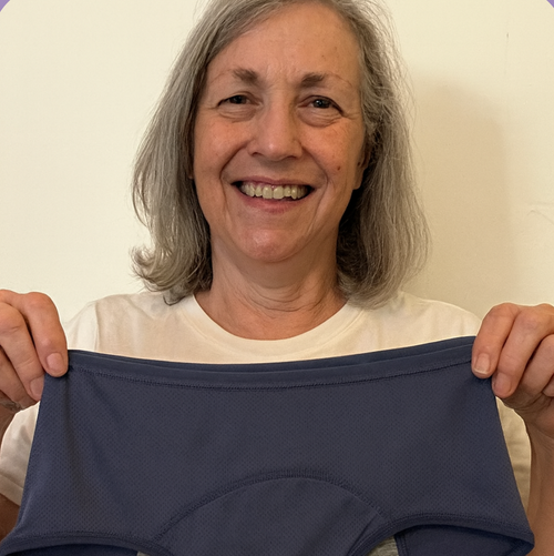 Person holding a pair of navy blue underwear against a plain background
