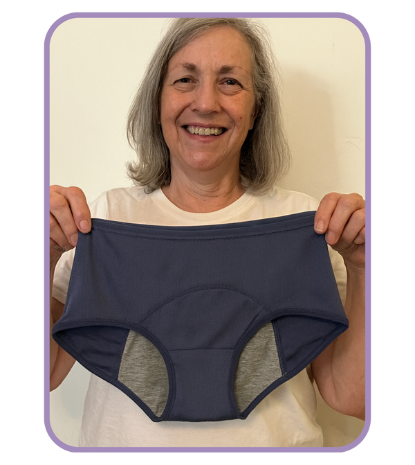 Person holding a pair of navy blue underwear against a plain background